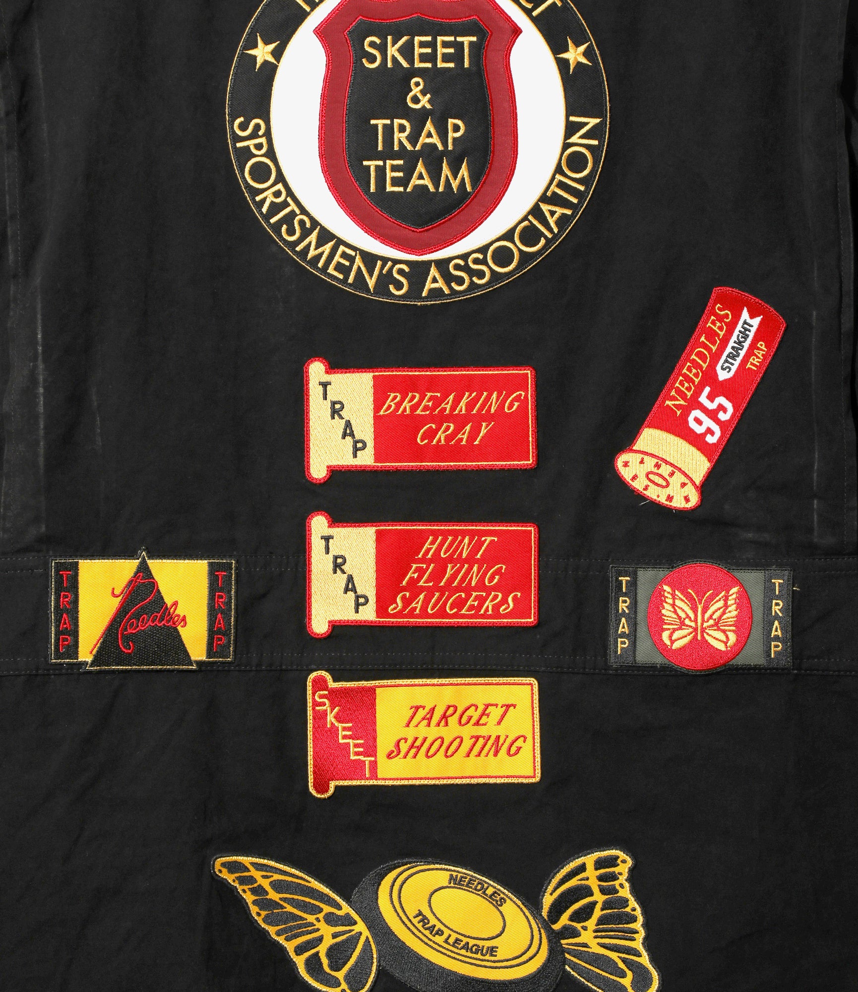 Black jacket with various patches including 'Skeet & Trap Team' and hunting-themed designs.