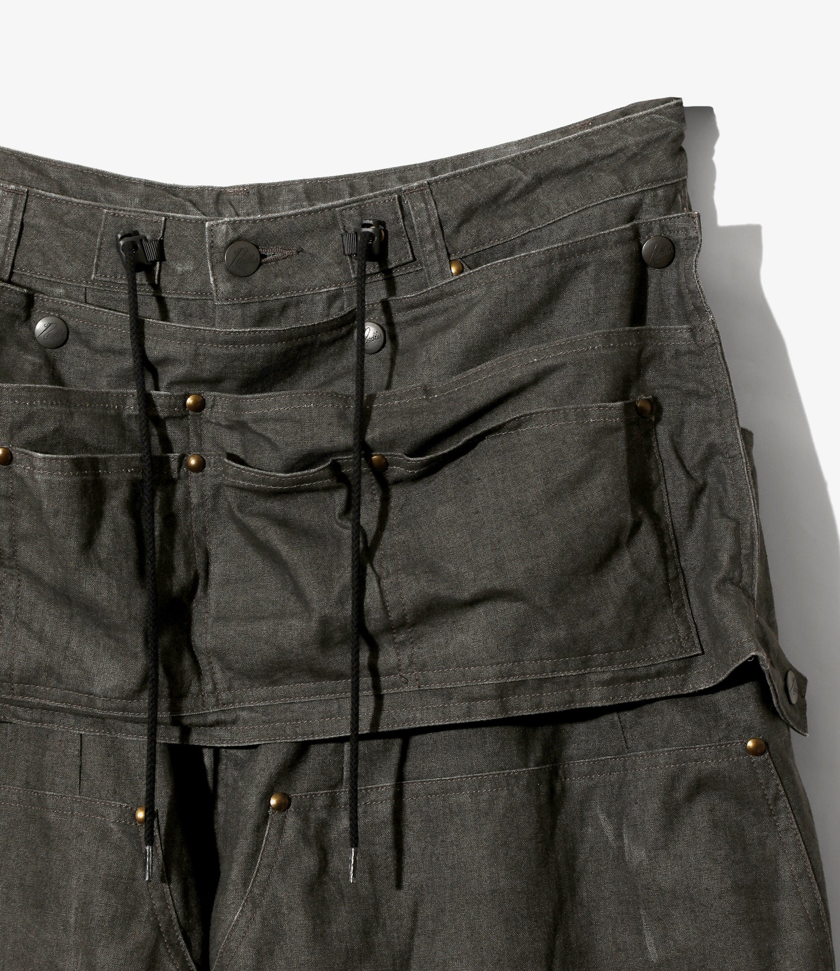 Dark gray work pants with apron and multiple pockets and drawstrings on a white background