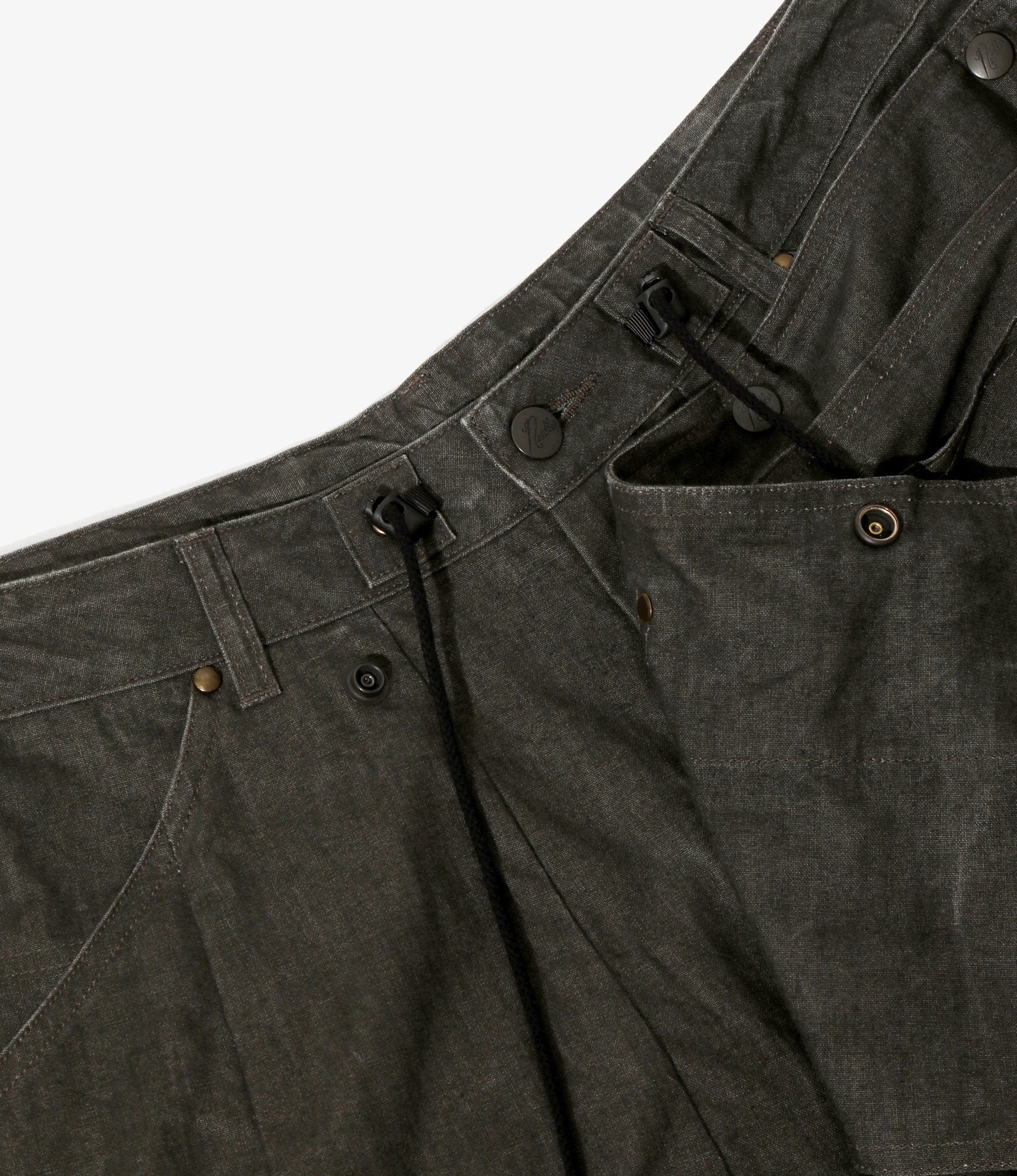 Close-up of dark gray pants with button details on a light gray background